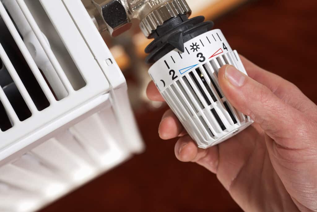 Thermostat wird an Heizkörper eingestellt.