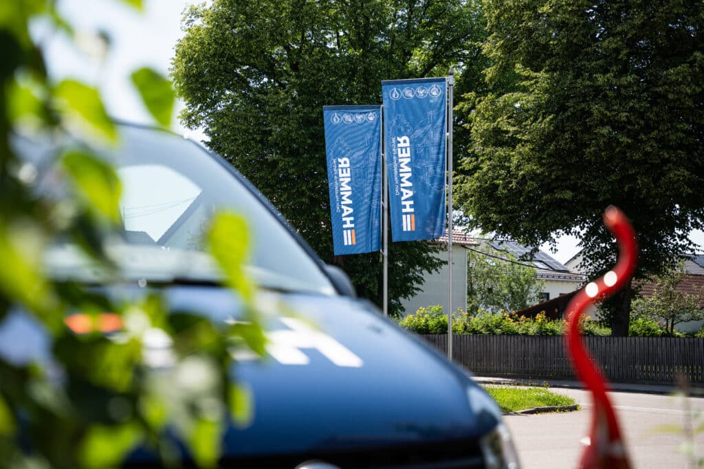Blaue Fahnen und Auto im Freien vor Bäumen.
