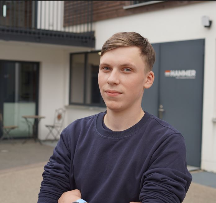 Person steht draußen vor Gebäude.