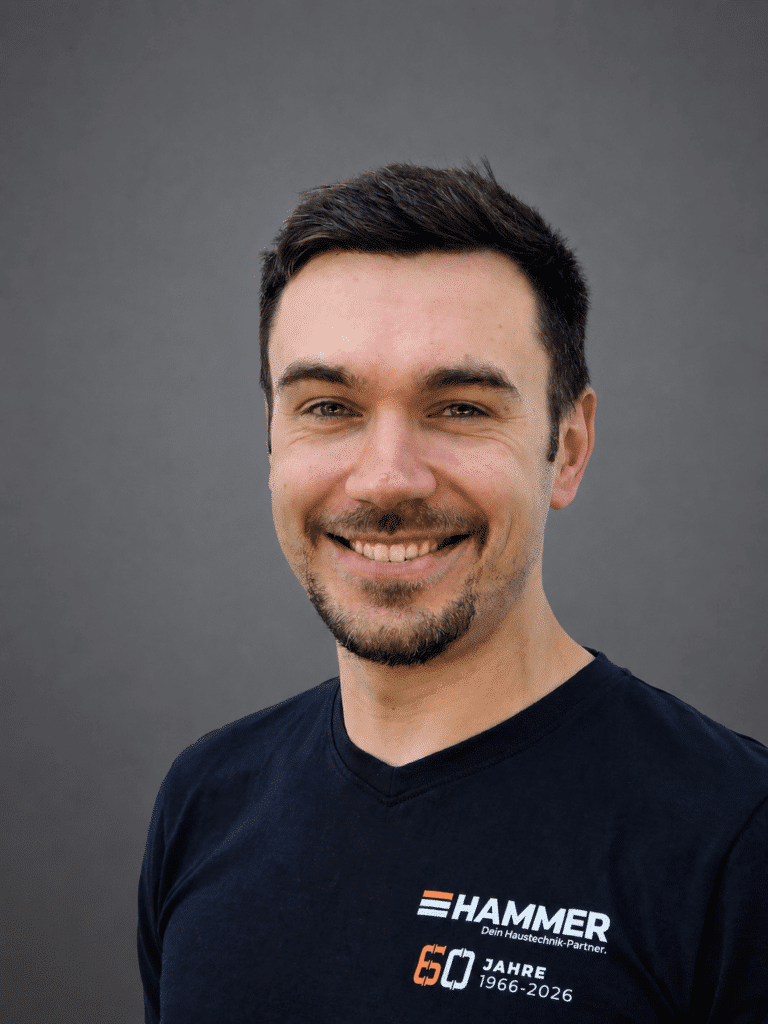 Lächelnder Mann im Firmen-T-Shirt vor grauem Hintergrund